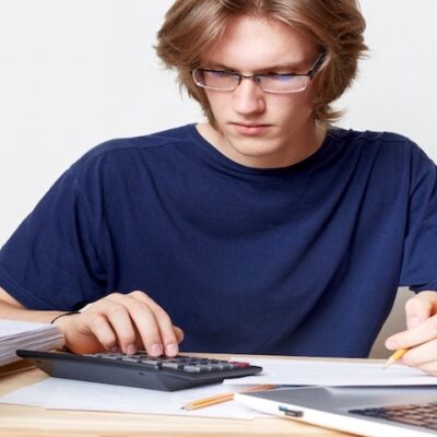 Voice over buyout. Close up portrait of a man calculating voice over fees for a TV commercial. This image is used to illustrate the article “Voice Over Buyouts and Usage Fees.” Freepik license: https://www.freepik.com/free-photo/man-faces-financial-crisis-studies-notification-from-bank-calculates-figures-male-student-studies-math-prepares-report_8987976.htm